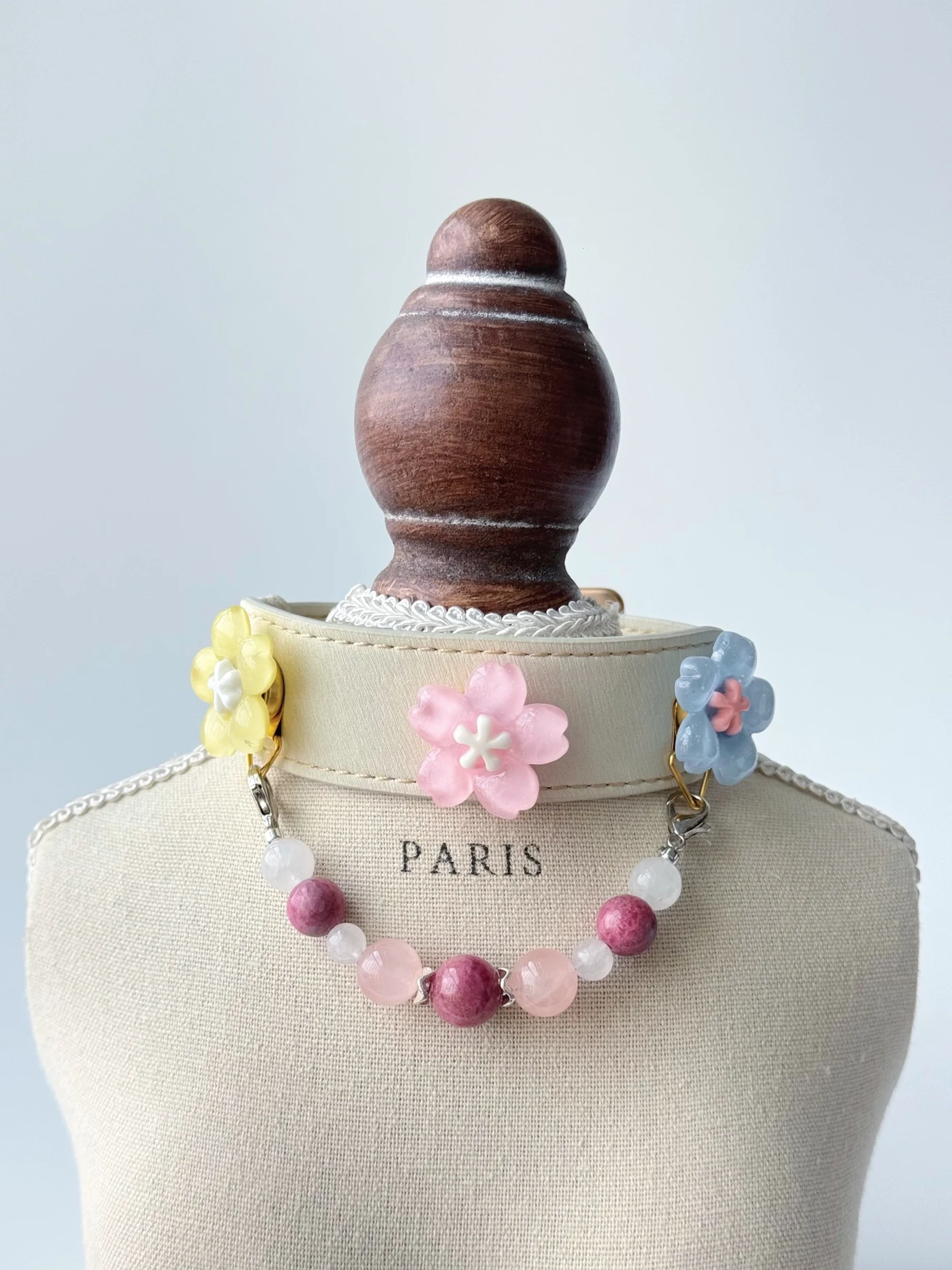 Ivory Rose Quartz Garden collar on a display bust with pastel flower ornaments and a pink and white decorative bead strand